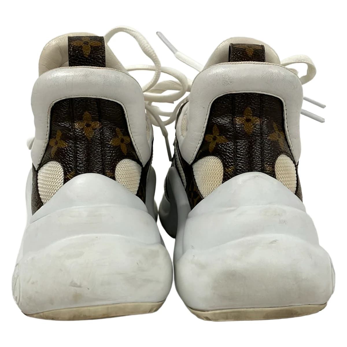 Dark brown and white low-top trainers shown from the side.