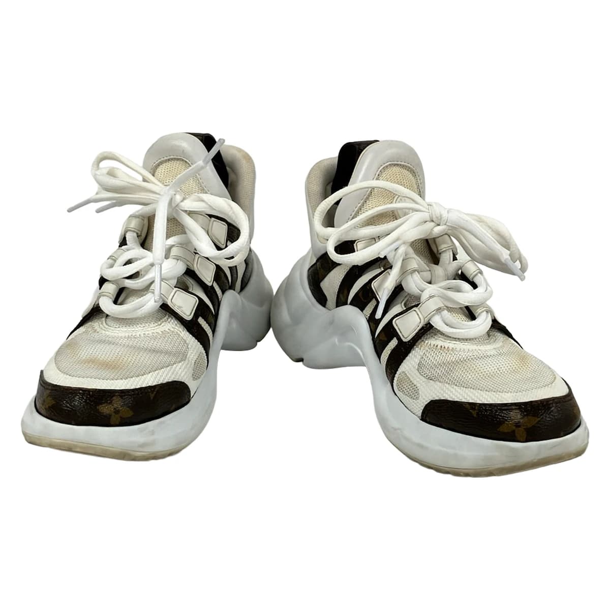 Dark brown and white low-top trainers shown from the side.