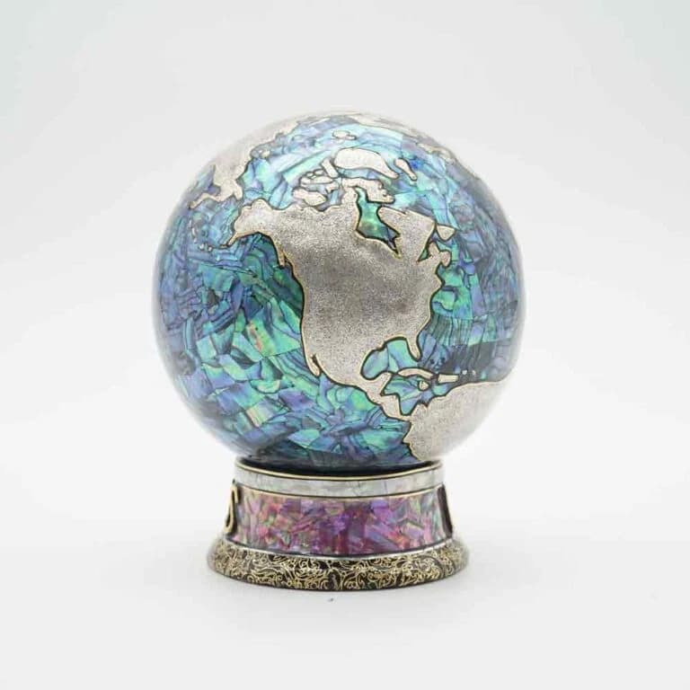 Product photograph of a small rounded vinyl figure with iridescent shell inlay decoration.