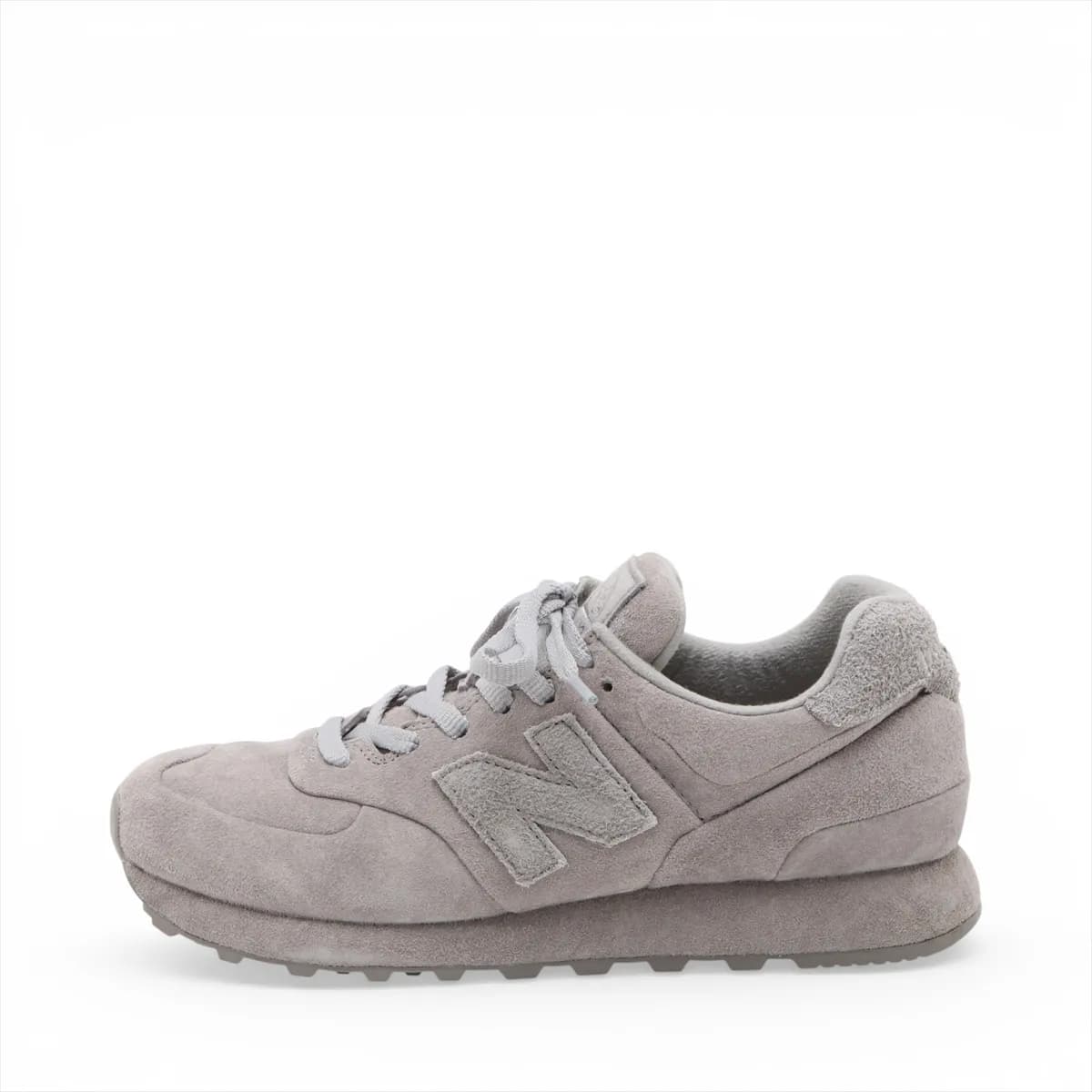 Pair of low-top grey suede sneakers in side view with mesh panelling and a white midsole.