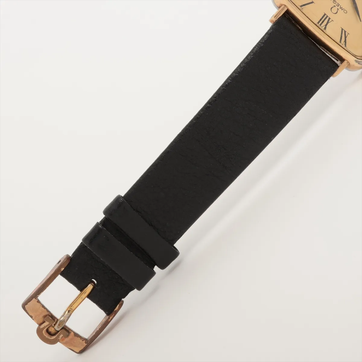 Small gold-tone watch with warm champagne dial and slim baton hands, fitted to a leather strap.
