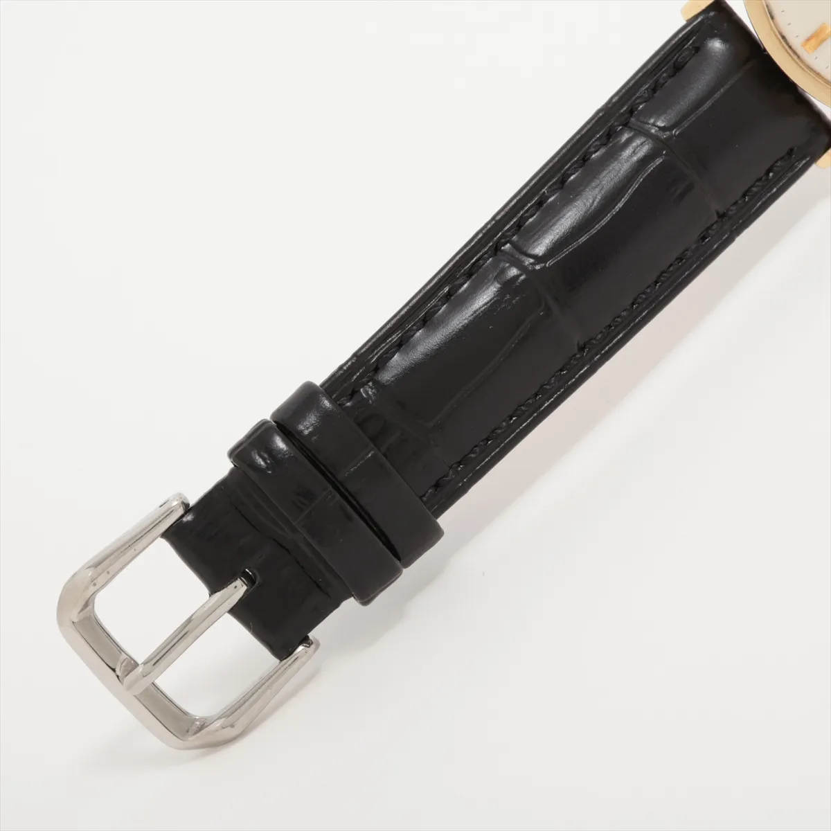 Gold-cased vintage watch with aged silver dial, slim hands and a leather strap.