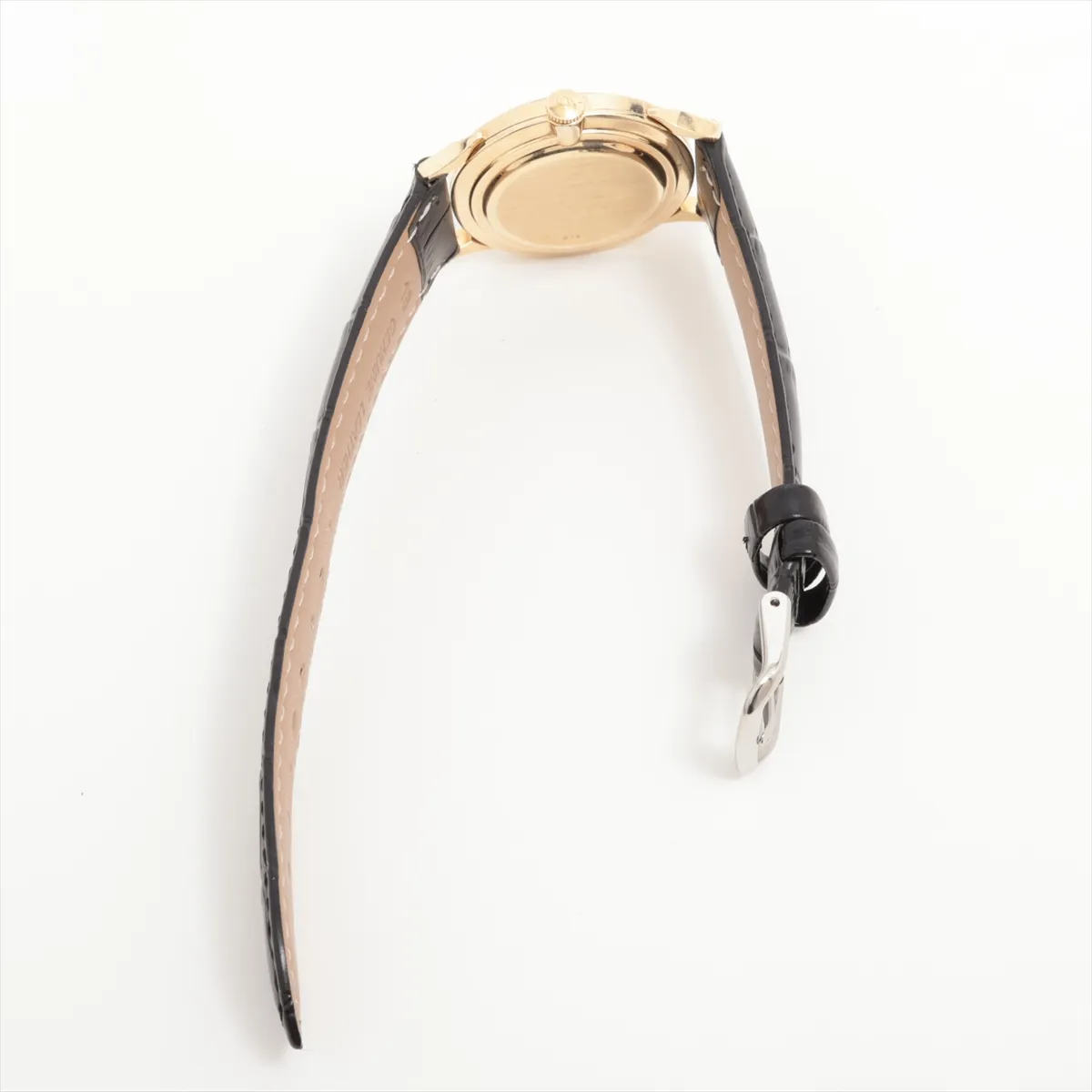 Gold-cased vintage watch with aged silver dial, slim hands and a leather strap.