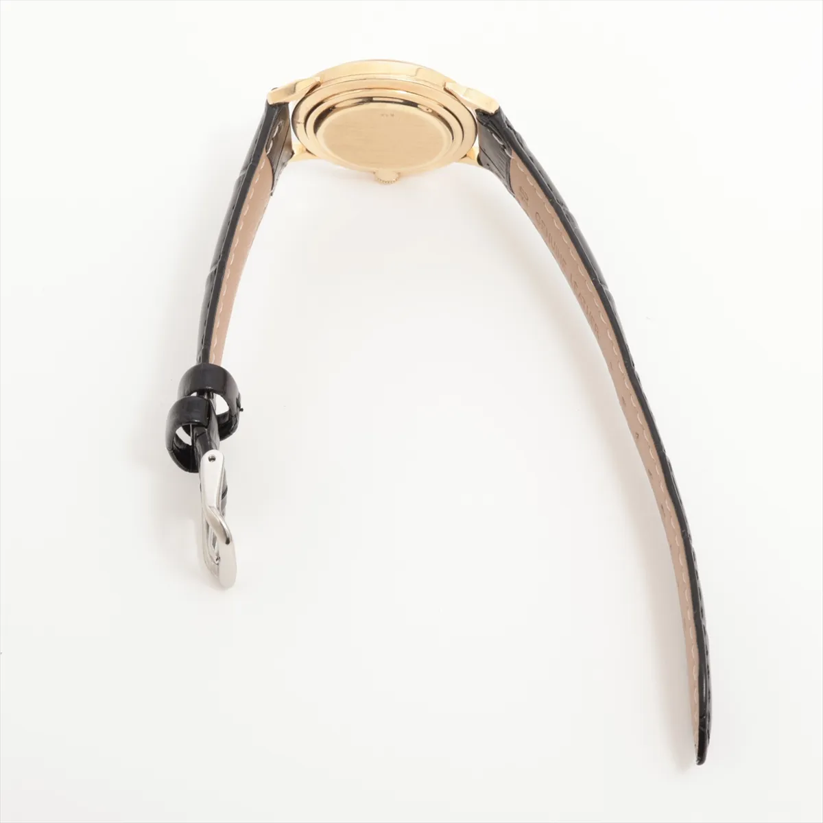 Gold-cased vintage watch with aged silver dial, slim hands and a leather strap.