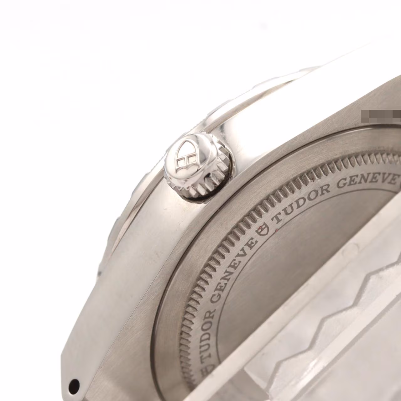 Stainless steel wristwatch with integrated bracelet and fluted bezel on a pale background.